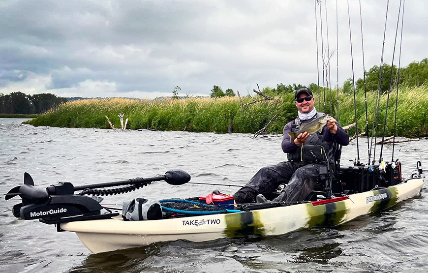 angler in a taketwo jackson kayak holding a fish with a bow-mounted motorguide trolling motor on the front